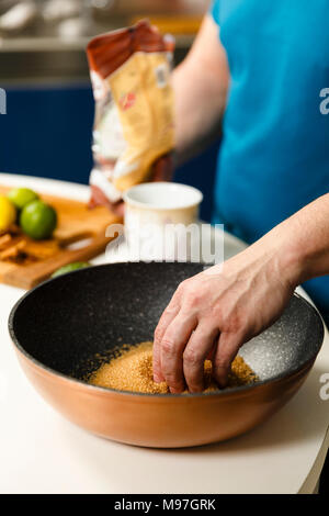 Mann Zutaten hinzufügen Zu karamellisierten Zucker in einem Wok Stockfoto