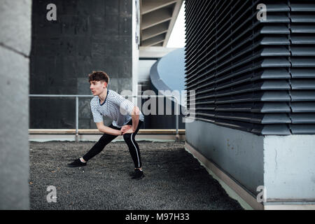 Freerunner dehnt sein Bein Muskeln auf einem Dach. Stockfoto