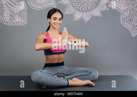 Angenehme junge Frau lächelnd während der Sitzung in einer Lotus darstellen Stockfoto