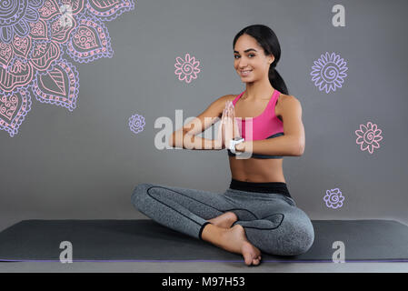 Angenehme junge Frau lächelnd, während sie Yoga Übungen Stockfoto