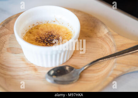 Crème Brûlée, auch als Gebrannte Creme bekannt, ein Dessert mit reichen Vanillepuddingunterseite und Karamell überstieg, auf Holzplatte Stockfoto