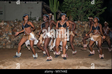 Hoedspruit, Südafrika, 09-03-2014, afrikanischer Mann eine Frau tanzen in traditioneller Kleidung am Lagerfeuer für Touristen, der Tanz ist ewen Wee in der Fertig Stockfoto