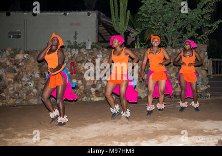 Hoedspruit, Südafrika, 09-03-2014, afrikanische Frau tanzen in traditioneller Kleidung in orange und rosa Farben am Lagerfeuer für Touristen, der Tanz ist nicht Stockfoto