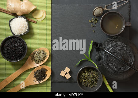 Grüne japanische und chinesische Tee mit traditionellen Nahrungsmitteln auf schwarzen Stein Tabelle einrichten. Ansicht von oben mit der Kopie. Stockfoto