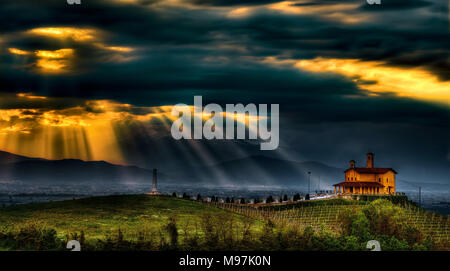 Spektakulär Klingen des Lichts Filter durch die dramatische Wolken, die parteiliche Schrein von Bastia Mondovì, in den Langhe, Piemont, Italien dominieren. Stockfoto