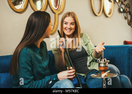 Zwei glückliche Frauen sitzen im Shisha Bar und Rauchen nargile Stockfoto