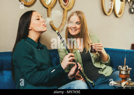 Zwei glückliche Frauen sitzen im Shisha Bar und Rauchen nargile Stockfoto