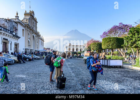 Antigua, Guatemala - März 18, 2018: Touristen in der Straße an der Kathedrale & Central Park als Einheimische bilden die fastenzeit Prozession Teppich mit Agua Vulkan hinter Stockfoto