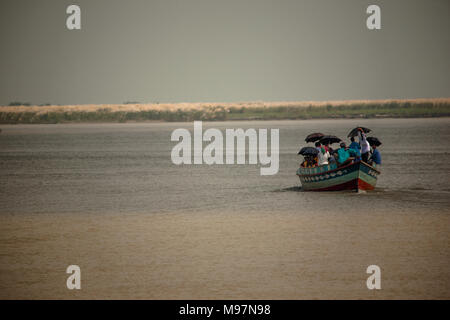 Eine unkonventionelle Wassertaxi trägt ein Boot Last der Menschen, die Sonnenschirme für Sun Abdeckung über dem Fluss Padma, Bangladesch verwenden. Stockfoto