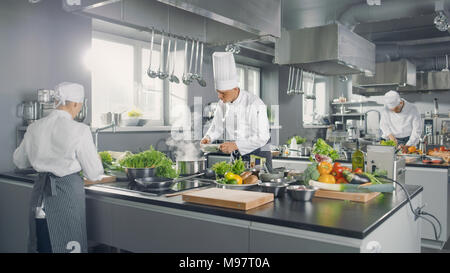 Große und glamouröse Restaurant besetzt Küche, Köche und Köchinnen Arbeiten auf ihren Gerichten. Stockfoto