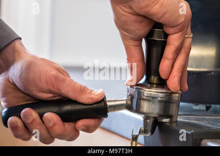 Barista drücken frisch gemahlenen Kaffee mit Stampfer in portafilter Cappuccino oder Espresso zu machen. Stockfoto