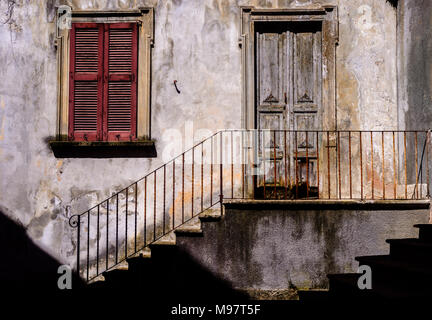 Traditionelle Sonne - Rustikale italienische Architektur Fassade mit Treppen Geländer neben Eisen führt zu abgenutzt, Treppen und hölzerne Tür leuchtet Stockfoto