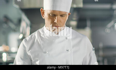 Dem berühmten Küchenchef konzentrierte sich auf die Zubereitung von Fisch Gericht auf der Pfanne. Er arbeitet in einer modernen Küche. Stockfoto