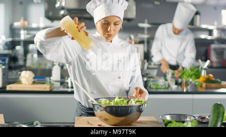 In einem berühmten Restaurant weiblichen Koch bereitet Salat, ads Öl. Sie arbeitet in einem großen, modernen Küche. Stockfoto