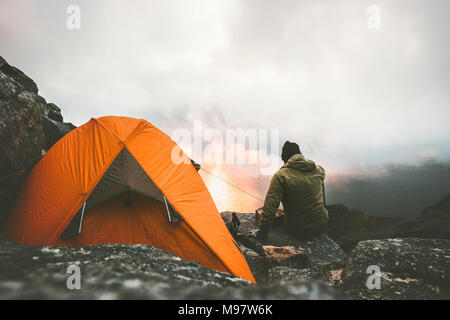 Der Mensch allein reisenden Sonnenuntergang in den Bergen in der Nähe von Zelt Camping outdoor Travel Abenteuer lifestyle Konzept wandern Wanderlust vacatio Stockfoto