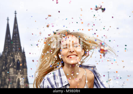 Deutschland, Köln, Portrait von Happy blonde Frau in zwischen Dusche Konfetti Stockfoto