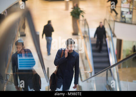 Mann am Telefon stehen auf Rolltreppe in einem Einkaufszentrum Stockfoto