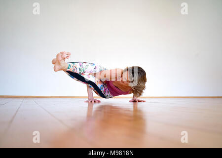 Reife frau yoga auf Fußboden im leeren Raum Stockfoto