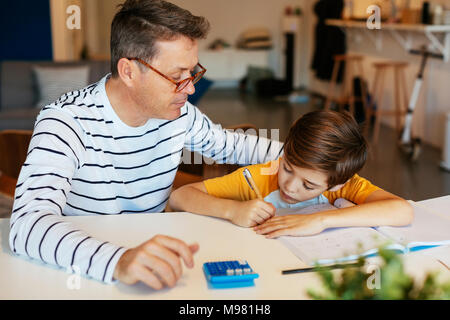 Vater, Sohn Hausaufgaben am Tisch Stockfoto