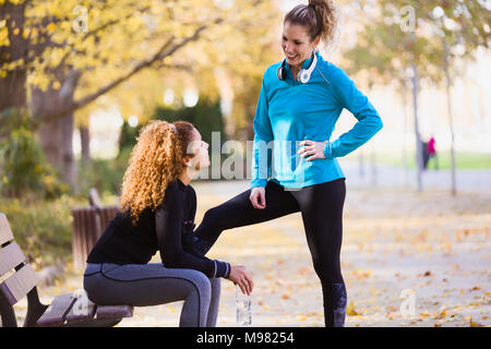 Zwei sportliche junge Frauen sprechen in Park Stockfoto