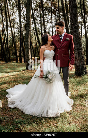 Glückliche Braut und Bräutigam stehen im Wald Stockfoto
