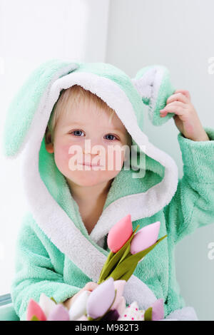 Cute Baby boy in ein Hase Kostüm mit einem Blumenstrauß zum Muttertag. Osterhase, 8. März, Feder Stockfoto