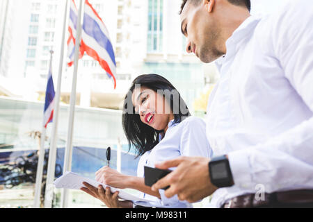 Thailand, Bangkok, Geschäftsmann und Geschäftsfrau in der Stadt mit Dokumenten, Handy und smartwatch Stockfoto