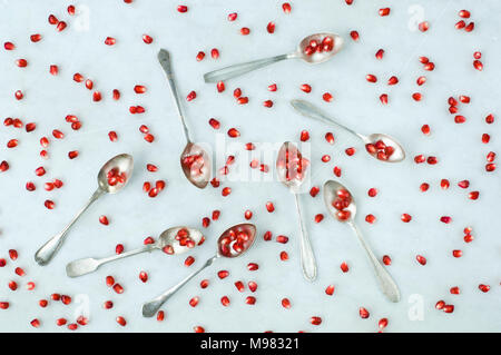 Granatapfel Samen und Silber Kaffee Löffel auf weißem Marmor Stockfoto