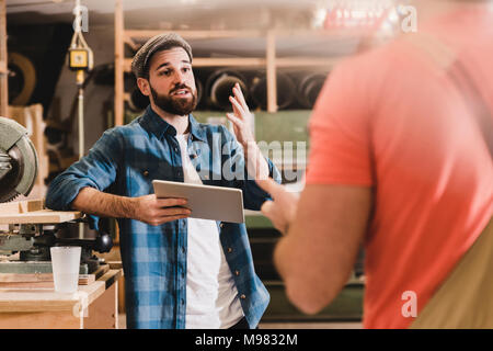 Zwei Männer mit Tablet diskutieren in der Werkstatt Stockfoto