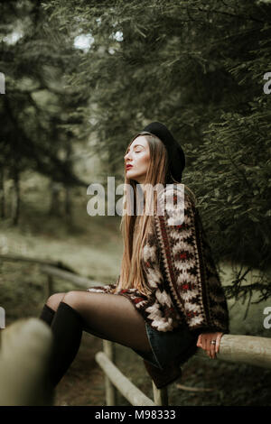 Modische junge Frau, die sich in die Wälder Stockfoto