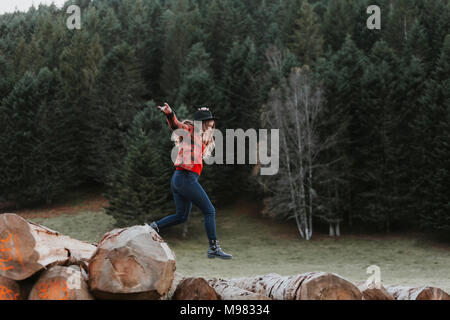 Junge Frau Balancieren auf Protokolle Stockfoto