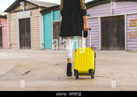 Rückansicht des Gehens Frau mit gelben Trolley bag, Teilansicht Stockfoto