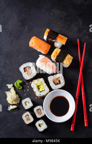 Vielzahl von Sushi mit Wasabi, Ingwer und Schüssel von sojasauce auf dunklem Boden Stockfoto