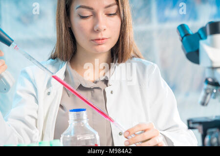 Junge Frau im wissenschaftlichen Labor mit Pipette und Chemikalien in den Reagenzgläsern Stockfoto