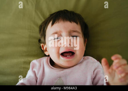 Porträt von weinenden Babymädchen auf Bett liegend Stockfoto