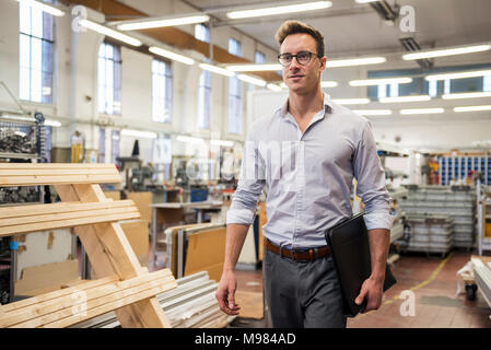 Junge Unternehmer gehen in Fabrik Ordner um: Stockfoto