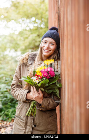 Porträt der lächelnde junge Frau Holding Blumenstrauß im freien Stockfoto