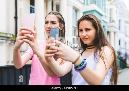 Zwei Mädchen im Teenageralter in der Stadt Nebeneinander selfies unter Stockfoto