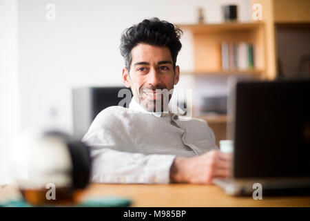 Portrait von entspannt Geschäftsmann am Schreibtisch Stockfoto