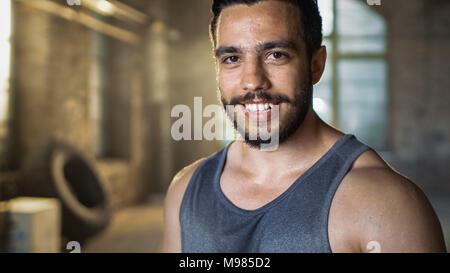 Schön verschwitzt muskulösen Mann lächelt auf Kamera. Schweiß tropfte von seinem Gesicht ist, trägt er Singlet. Stockfoto