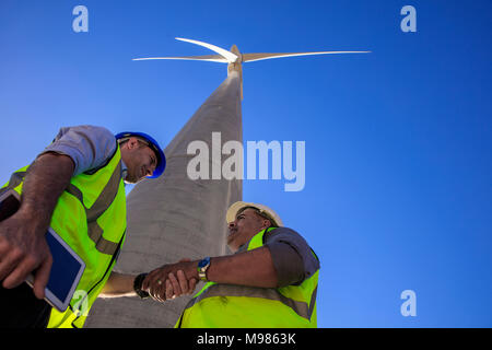 Low Angle View der Techniker die Hände schütteln vor Wind Turbine Stockfoto