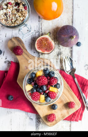 Glas natürliches Joghurt mit Müsli und verschiedene Früchte Stockfoto