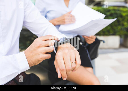 Geschäftsmann mit smartwatch und Geschäftsfrau mit Dokumenten, die in der Stadt Stockfoto