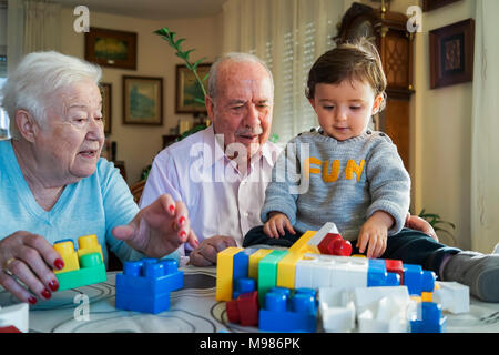 Urgroßeltern und Baby Mädchen spielen zusammen mit Kunststoff Bausteine zu Hause Stockfoto