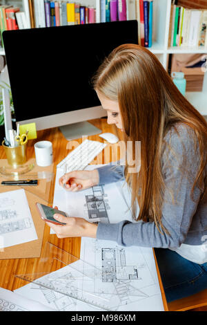 Junge Frau, die in der Architektur Büro, per Telefon Stockfoto