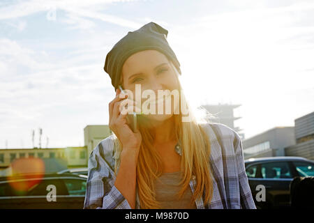 Portrait von Happy blonde Frau am Telefon mit Hintergrundbeleuchtung Stockfoto