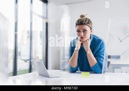 Porträt der jungen Frau mit Laptop auf dem Schreibtisch im Büro Stockfoto