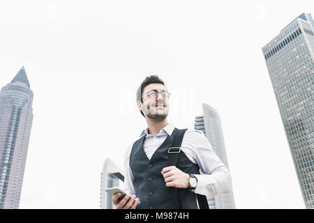 Deutschland, Frankfurt, selbstbewussten jungen Geschäftsmann mit Mobiltelefon in der Stadt Stockfoto