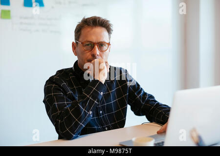 Porträt von Ernst Kaufmann mit Laptop auf dem Schreibtisch im Büro Stockfoto