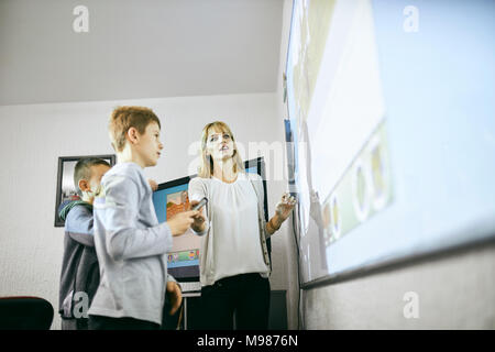 Lehrer mit Schülern im Unterricht am interaktiven Whiteboard Stockfoto